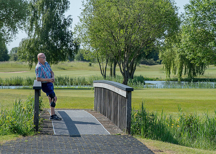 Person mit einer Knieorthese von Össur steht auf einer Brücke