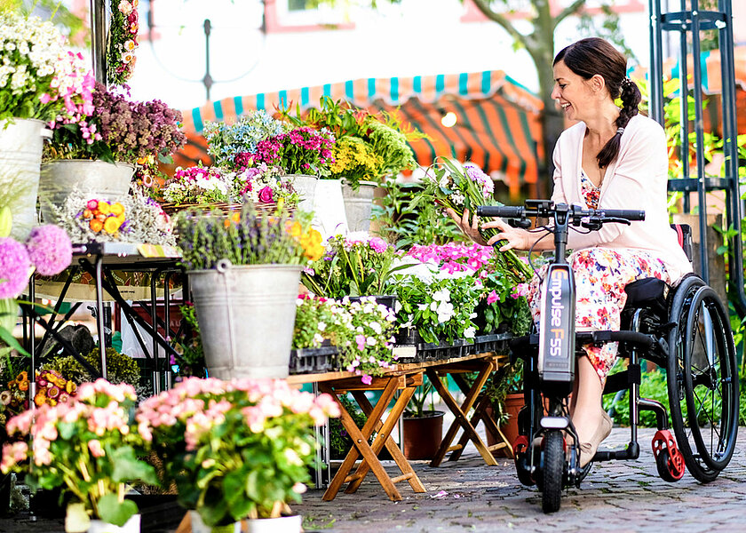 Frau mit Rollstuhl am Blumenladen